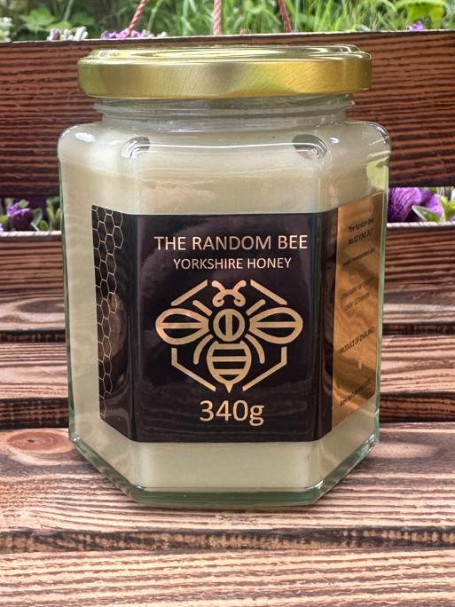 Jar of creamed honey from 'The Random Bee' 340g on a wooden surface with a blurred natural background