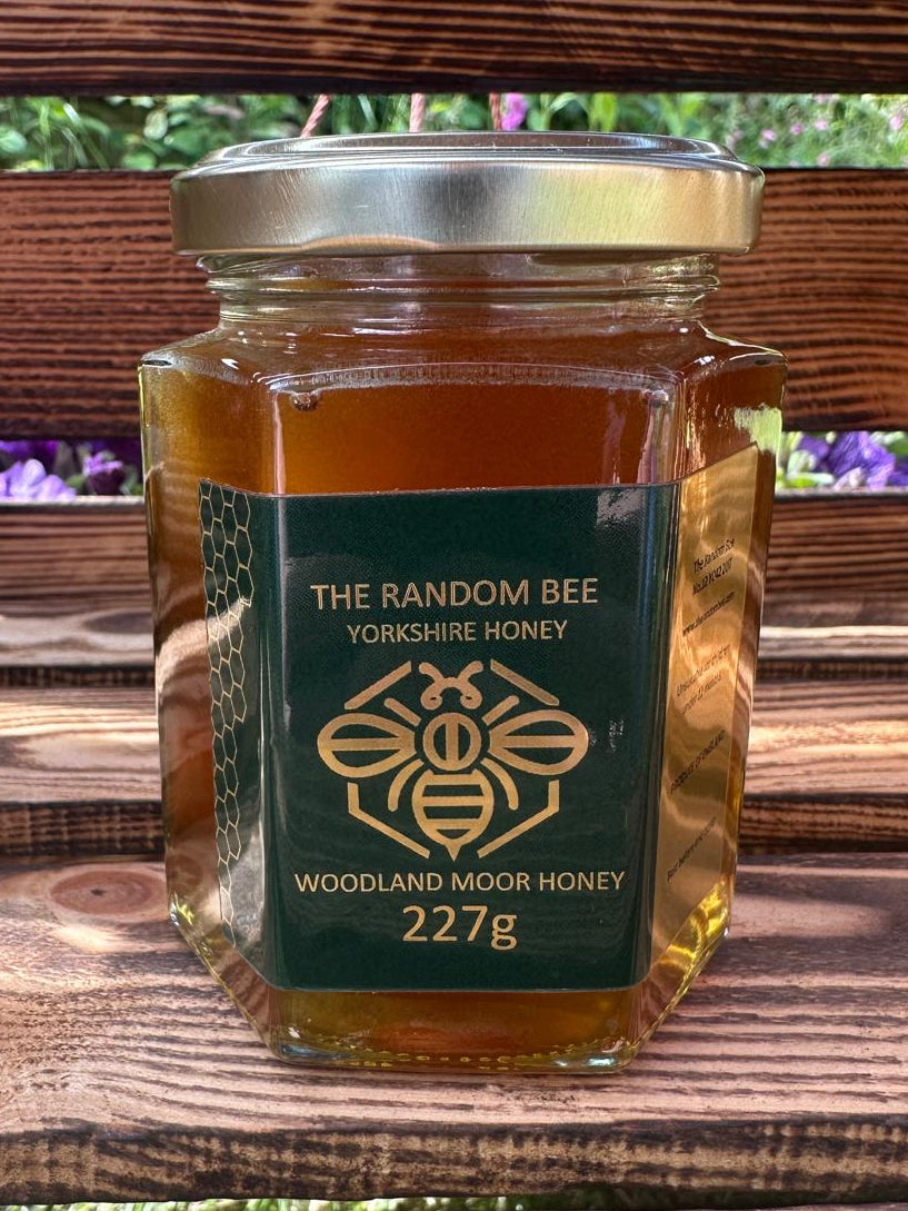 Jar of 'The Random Bee' Yorkshire Honey Woodland Moor Honey 227g on a wooden surface with a blurred natural background