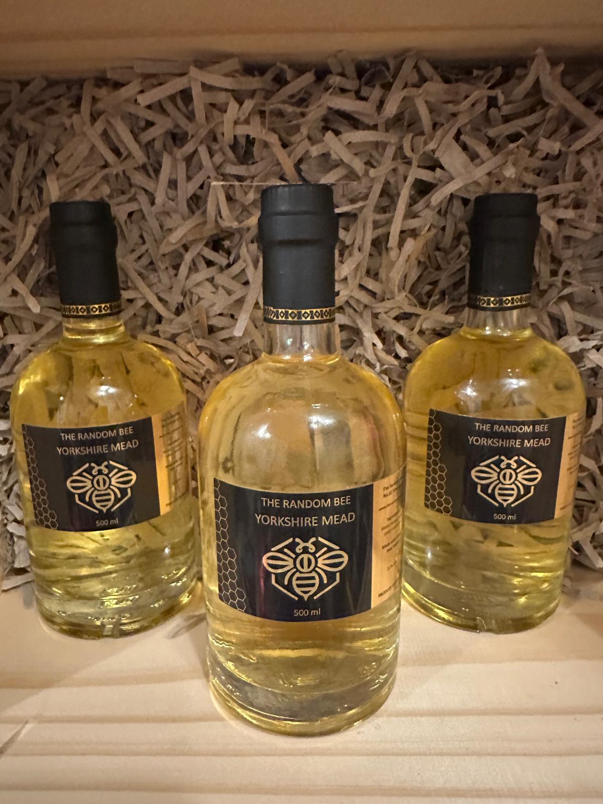 Three bottles of The Random Bee Yorkshire Mead against a decorative background.