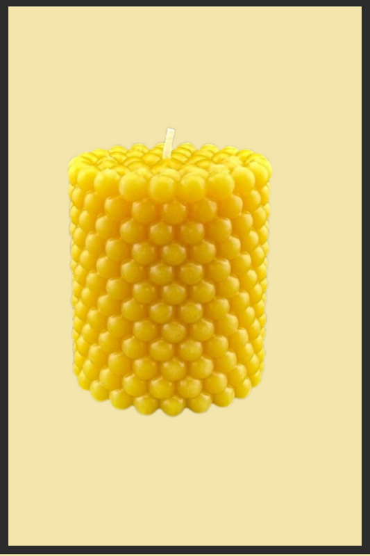 Yellow beehive-patterned candle on a beige background